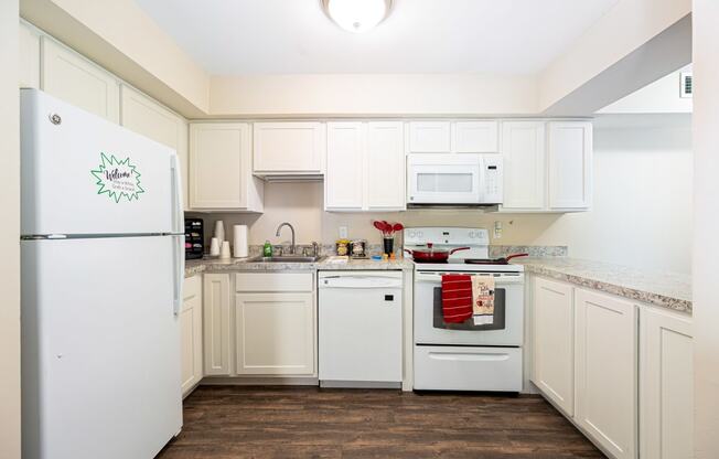 a kitchen with white cabinets and appliances and a white refrigerator