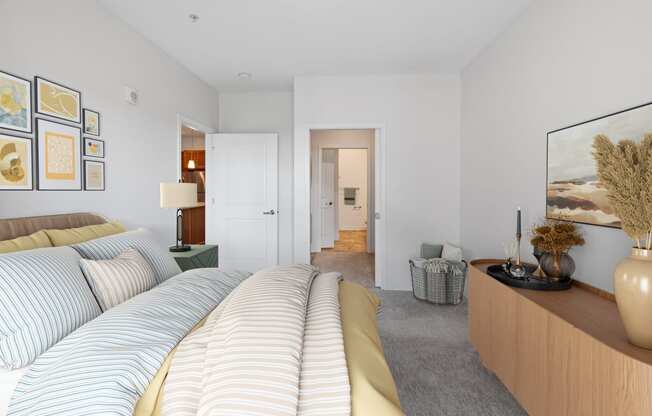 a bedroom with a bed and a dresser and a hallway to a bathroom