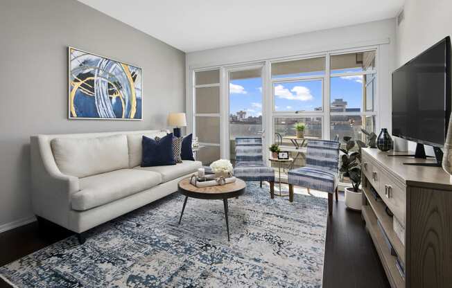 a living room with a white couch and a blue rug   and a window