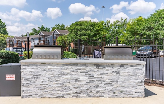 the clubhouse has a stone bar with two grills and a fence