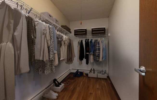 a walk in closet with a lot of clothes hanging on a rack and shoes on the floor