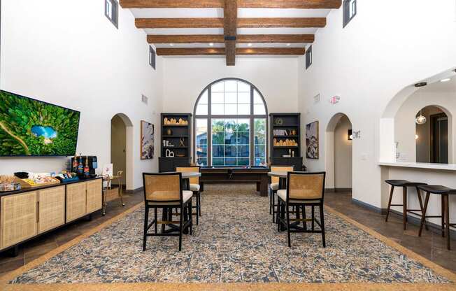 A living room with a large rug and a TV on the wall.