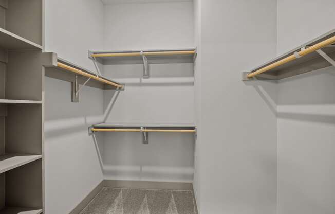 a walk in closet with empty shelves and a white wall