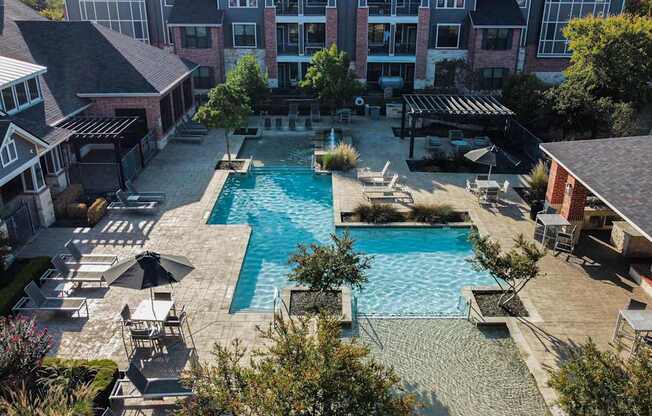 an aerial view of a swimming pool with lounge chairs and umbrellas