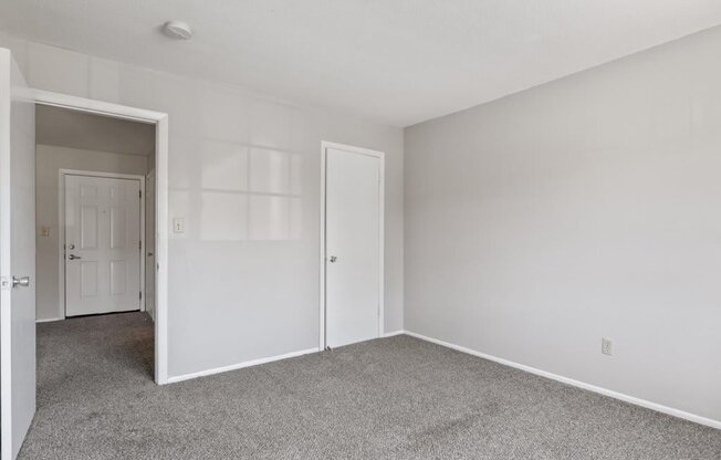 bedroom with white walls and a door to a closet