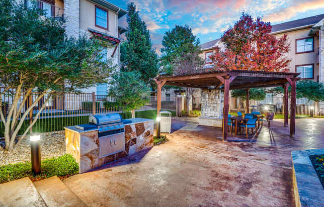 a patio with a grill and a picnic table in front of a building