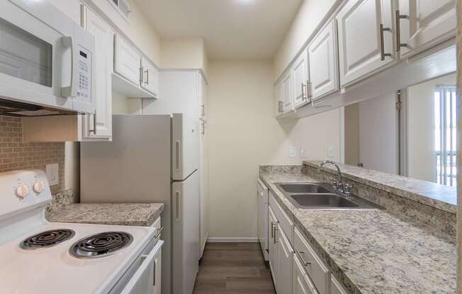 Kitchen with white cabinets and white appliances in a 2 bedroom, 1.5 bath 846 sq ft apartment home at The Biltmore Apartments located in the Vickery Midtown neighborhood of Dallas, TX.