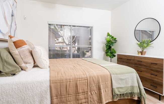 A bedroom with a bed, a dresser, and a mirror.