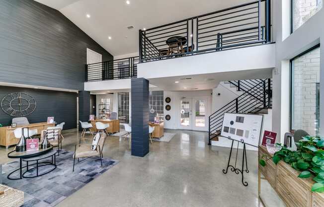 the lobby of a building with a staircase and tables and chairs