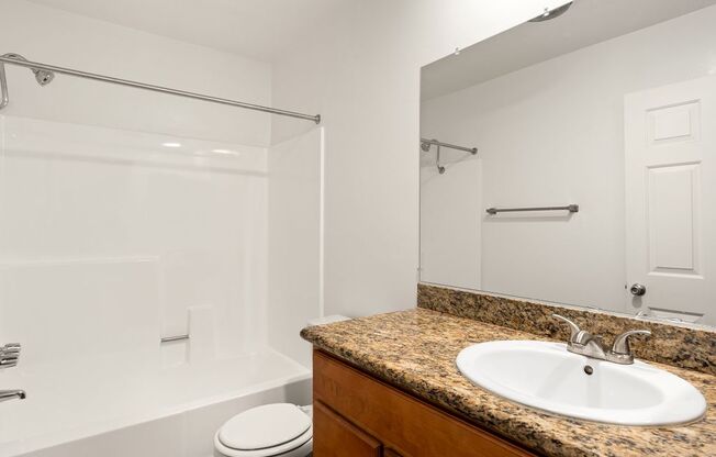 A bathroom with a granite countertop and a white toilet.