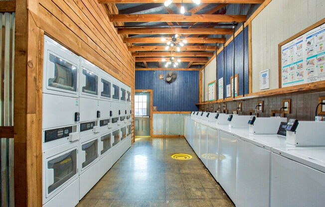 a laundry room with lots of white appliances and a long row of sinks