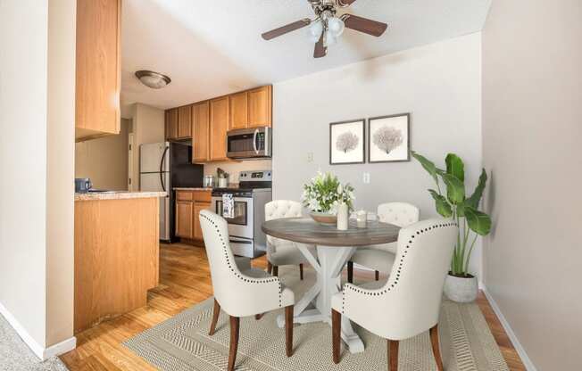 a dining area with a table and chairs and a kitchen in the background