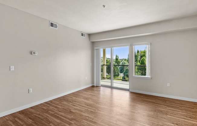 a bedroom with hardwood floors and a sliding glass door leading to a balcony