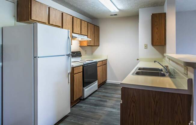 A kitchen with a white refrigerator and wooden cabinets.
