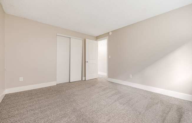 A room with carpeted floor and two doors.