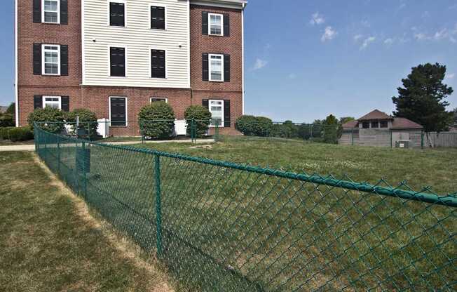 A green fence in front of a red brick building.