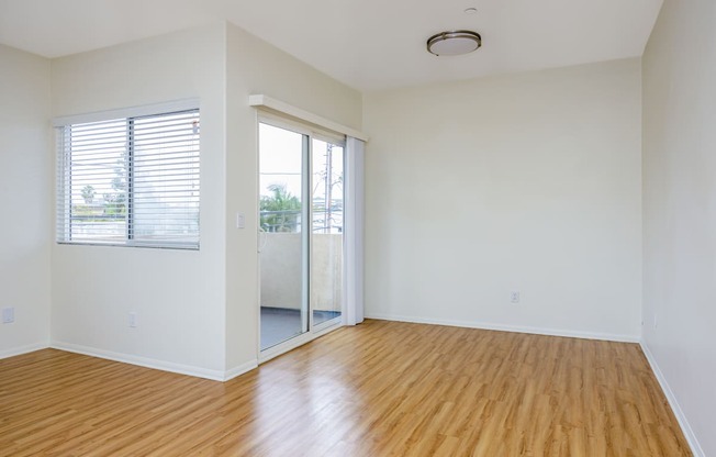 an empty living room with wood floors and a sliding glass door