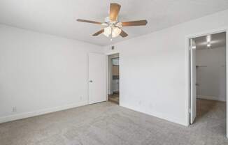 A room with a ceiling fan and carpeted floor.