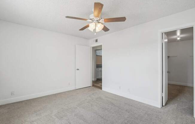 A room with a ceiling fan and carpeted floor.