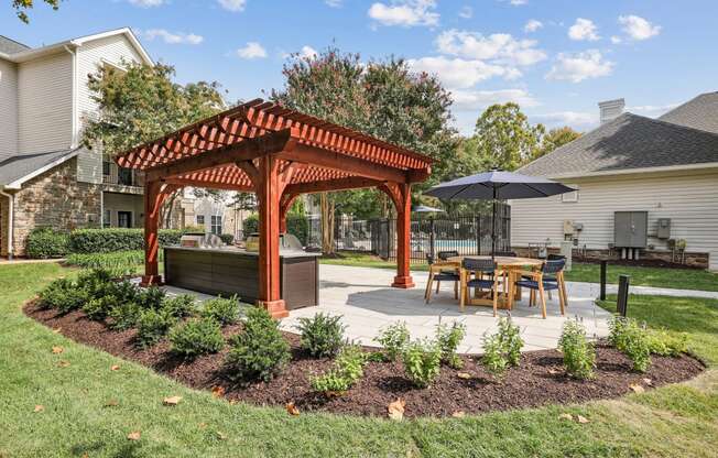 a pergola with a table and chairs in a backyard