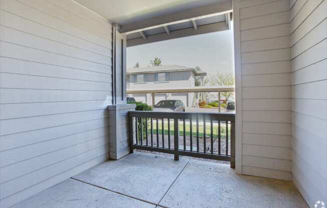 the view from the front porch of a home with a balcony and a driveway