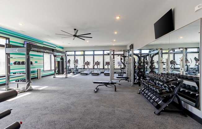 A spacious gym with a variety of equipment and a flat screen TV mounted on the wall.