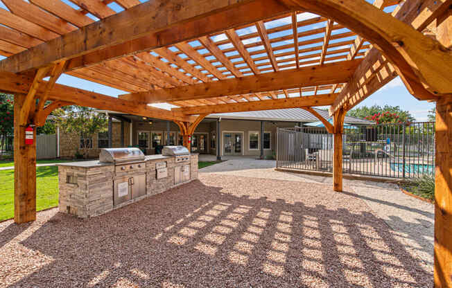 a patio with a stone grill and a wooden roof