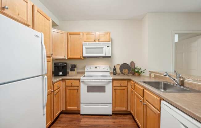 a kitchen with wooden cabinets and a white stove and refrigerator at Residences at Manchester Place in Manchester New Hampshire