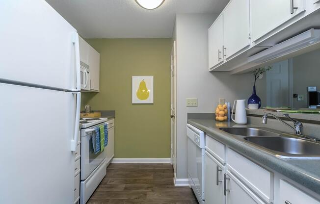 A kitchen with white appliances and cabinets at Ashley Oaks Apartments in Greensboro, North Carolina