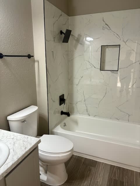 A white toilet sits next to a white bathtub in a bathroom.