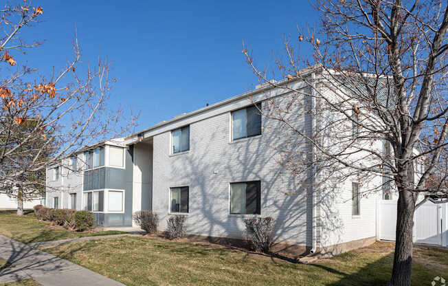 A modern building with a grey facade and a white fence in front.