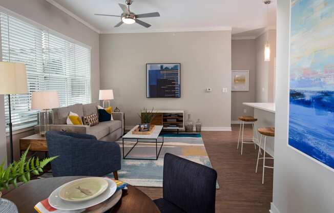 a living room with a couch and a table and a ceiling fan at One Riverside Apartments, Chattanooga