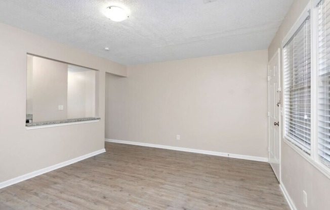 the spacious living room with a large window and white walls