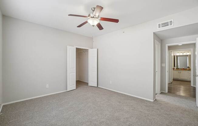 A room with a ceiling fan and carpeted floor.