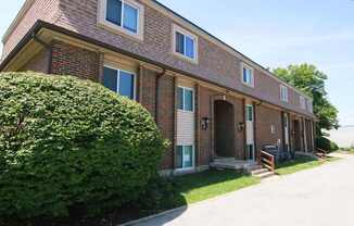 A red brick house with a green bush in front.