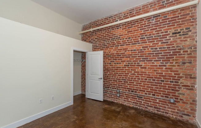 a room with a brick wall and a white door at Mayton Transfer Lofts, Petersburg, VA