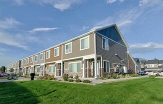 a row of houses with a green lawn and a blue sky