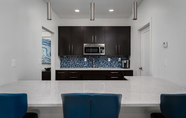 a kitchen with a large island with a white counter top and blue chairs