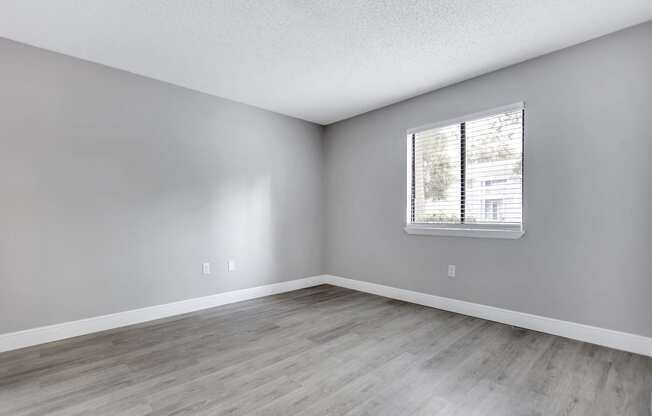 an empty room with wood floors and a window