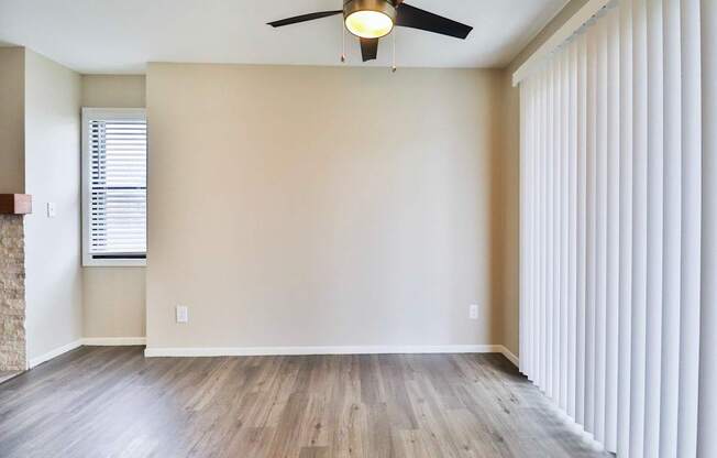 A room with a ceiling fan and a window with blinds.