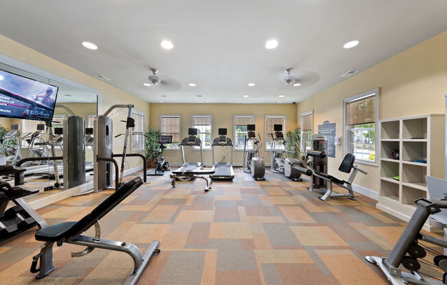 Fenwyck Manor's fitness center with cardio and strength equipment, a TV, and a mirrored wall