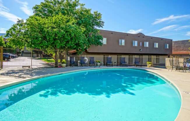 A large swimming pool in front of a building with a fence around it.