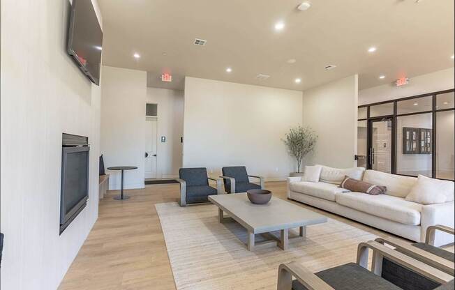 A living room with a white couch, a black television, and a wooden coffee table at Northplace Apartment Homes, Oregon