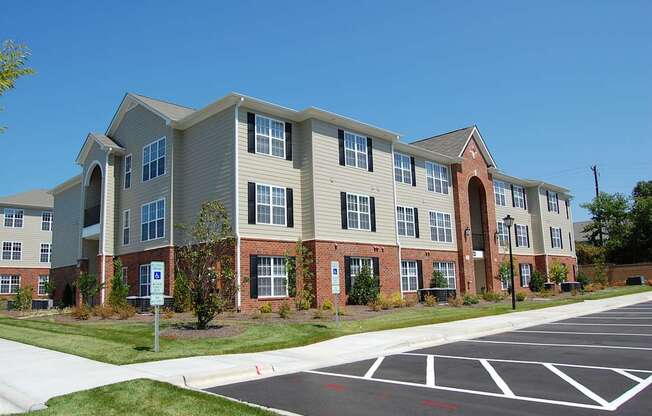 Apartment building with a parking lot in front.