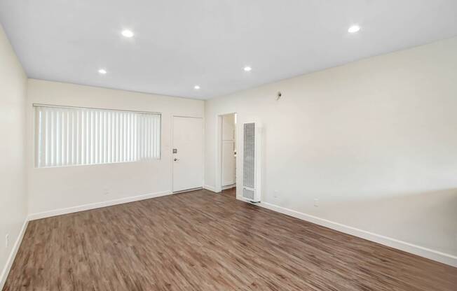 an empty living room with white walls and wood flooring