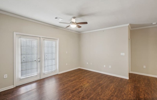 an empty living room with wood flooring and a ceiling fan