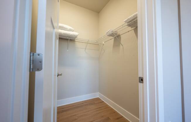 a walk in closet with a mirrored closet door and a wire rack