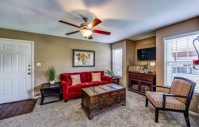 a living room with a red couch and a ceiling fan