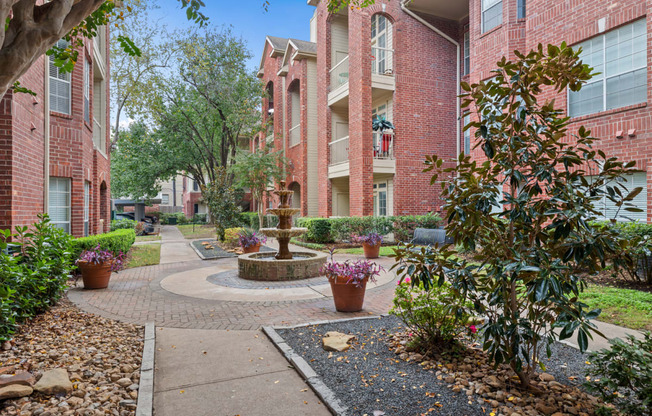 a fountain sits in the middle of a walkway in front of apartment buildings