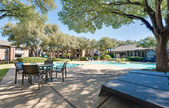 A pool surrounded by trees and chairs.